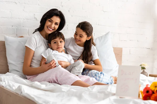 Happy Mother Hugging Adorable Children While Sitting Bed Bouquet Mothers — Stock Photo, Image