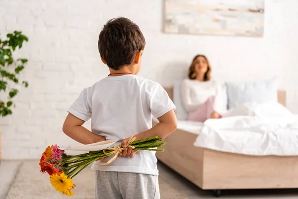 Вид Ззаду Хлопчика Тримає Квіти Листівку День Матері Мама Сидить — стокове фото