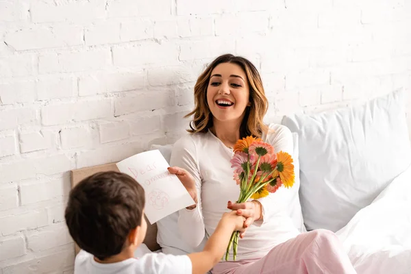 Back View Boy Presenting Flowers Mothers Day Card Happy Mom — 스톡 사진