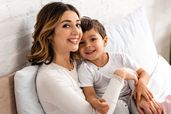 Happy Mother Son Smiling Camera While Sitting Bed Morning — Stock Photo, Image
