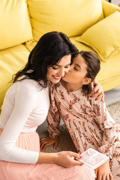 Feliz Mujer Sosteniendo Madres Día Tarjeta Mientras Adorable Hija Besándola — Foto de Stock