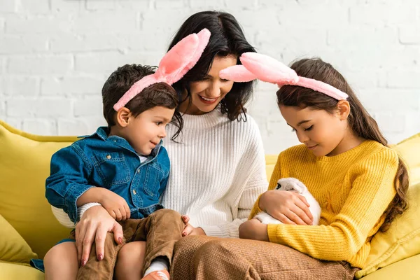快乐的女人 快乐的孩子 长着一对小白兔 坐在黄色的沙发上 — 图库照片