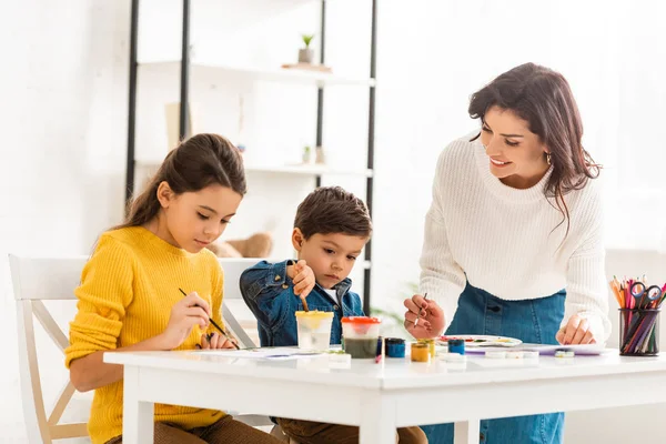 Glückliche Frau Die Tisch Steht Und Mit Kindern Mit Farben — Stockfoto