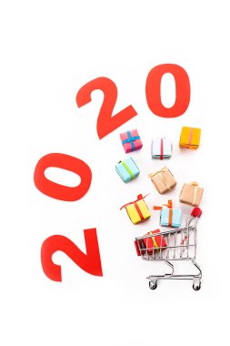 Hediye kutularının yanındaki dekoratif küçük alışveriş arabasının üst görüntüsü ve 2020 numara beyaz üzerinde izole edilmiş.