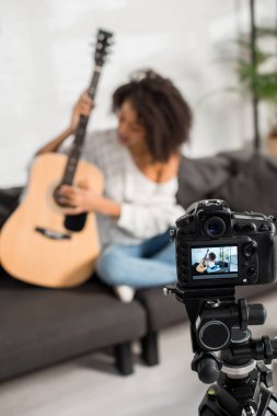 Genç Afrikalı Amerikalı kızın akustik gitar çaldığı dijital kameranın seçici odak noktası 