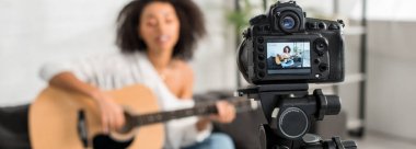 Afrika kökenli Amerikalı genç bir kızın akustik gitar çaldığı ve sergilendiği dijital kameranın panoramik görüntüsü. 