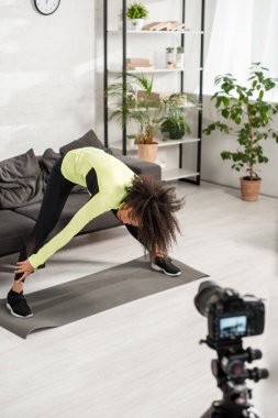 Sportif Afro-Amerikan video blogcusunun seçici odak noktası dijital kameranın yanında uzanan spor giyim. 