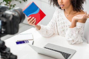 Ekranda tıbbi uygulama ve dijital kamera ile akıllı telefonun yanında renkli kutular taşıyan Afrikalı Amerikalı etkili kişinin görüntüsü. 