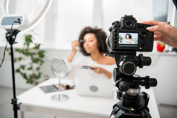 有选择的焦点女性接触数码相机靠近卷曲的非洲裔美国影响者在展示会上化妆 — 图库照片