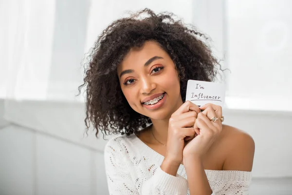 Cheerful African American Girl Braces Holding Card Influencer Lettering Home — Stock Photo, Image