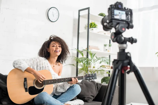 在数码相机附近弹奏声吉他的快乐非洲裔美国女孩的选择性聚焦 — 图库照片
