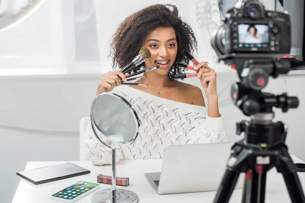 乌克兰基辅 2019年12月10日 快乐的非洲裔美国女孩在Iphone附近拿着唇彩和化妆品刷子的选择焦点 — 图库照片