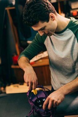 worker screwing snowboard binding to snowboard in repair shop  clipart