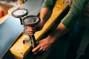 cropped view of worker holding grip vice in repair shop 