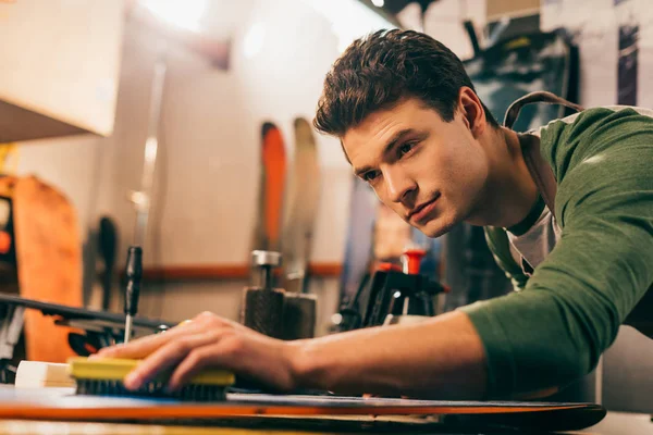 Selective Focus Worker Using Brush Snowboard Repair Shop — Stock Photo, Image