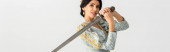 Panoramaaufnahme einer lächelnden Königin mit Schwert isoliert auf grau
