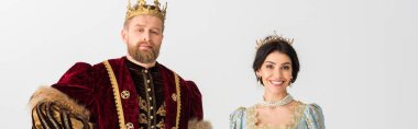 panoramic shot of smiling queen and king with crowns isolated on grey 