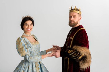 smiling queen and king with crowns holding hands isolated on grey 