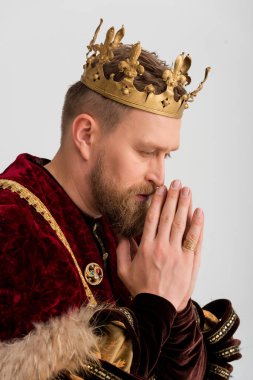 side view of king with crown praying isolated on grey 