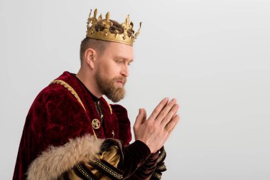 side view of king with crown praying isolated on grey 