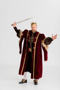 angry king with crown holding sword isolated on grey