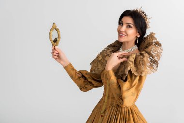 smiling queen with crown holding mirror isolated on grey