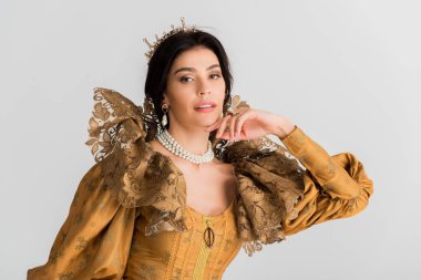 attractive queen with crown looking at camera isolated on grey