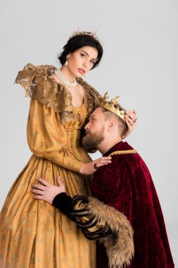 king with crown hugging attractive queen isolated on grey 