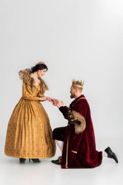 smiling queen and king with crowns holding hands on grey background 