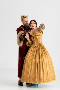 king with crown choking attractive queen on grey background 