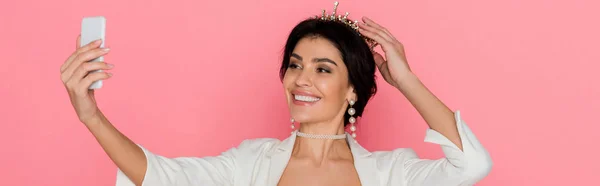 ピンクの背景で自撮り王冠と笑顔の女性のパノラマ写真 — ストック写真