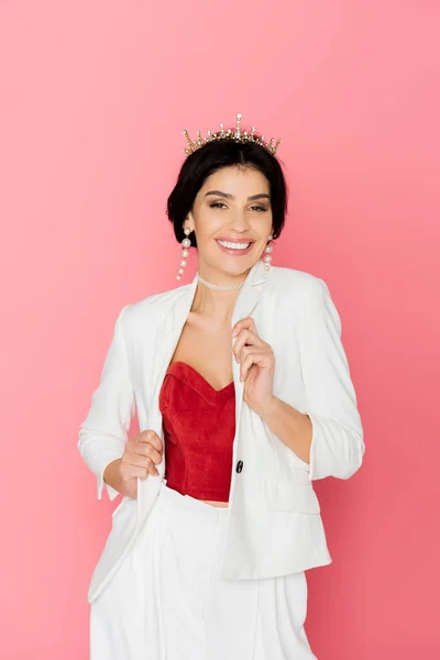 smiling woman with crown looking at camera on pink background