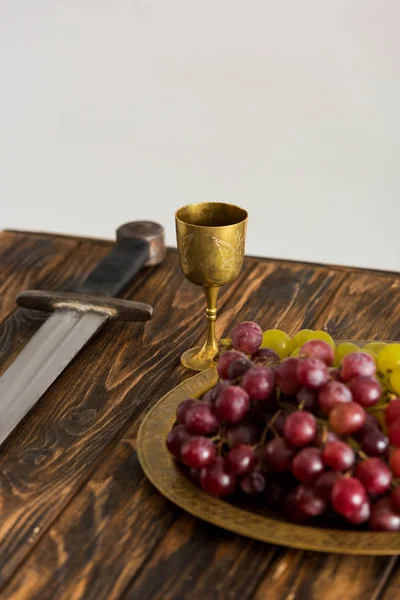 古老的杯子 剑和葡萄放在木制桌子上 与灰色隔离 — 图库照片