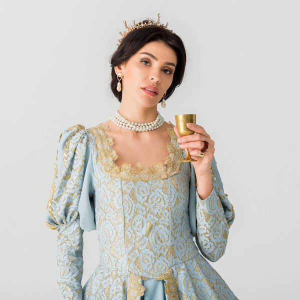 attractive queen with crown holding cup isolated on grey