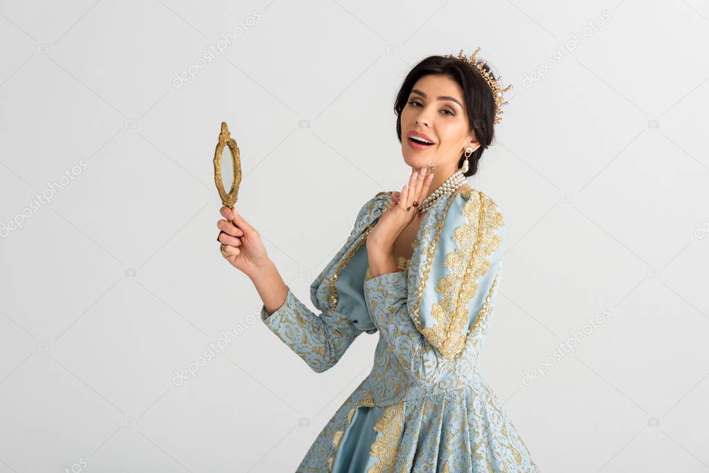 shocked queen with crown holding mirror isolated on grey