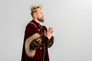 side view of king with crown praying isolated on grey