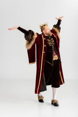 happy king with crown and outstretched hands on grey background 