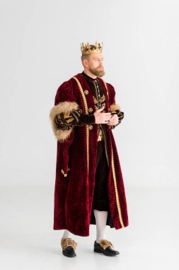 handsome king with crown looking away on grey background 