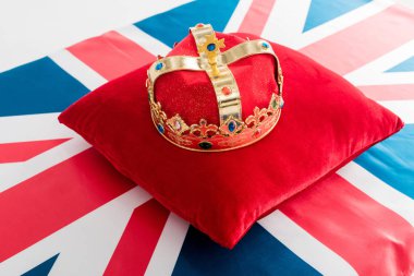 golden crown on red pillow and british flag 