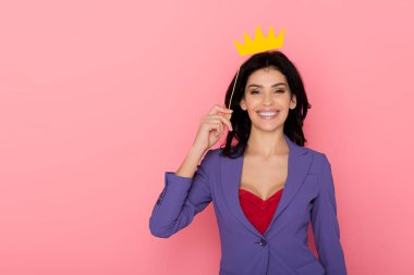 smiling woman holding paper crown on pink background  clipart