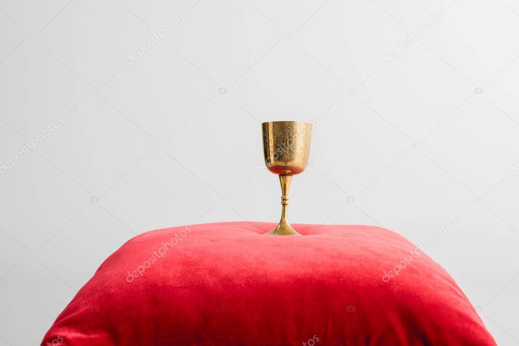 golden cup on red pillow isolated on white