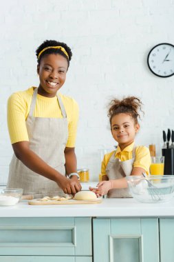 Neşeli Afrikalı Amerikalı anne ve kız mutfakta hamur köftesi yontuyorlar. 