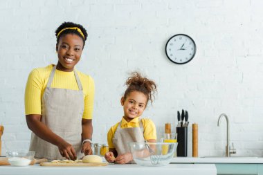 Neşeli Afro-Amerikan annesi ve tatlı kızı mutfakta hamur işi yapıyor. 