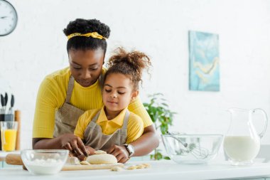 Afro-Amerikan annesi, sevimli çocuğun yanında mutfakta hamur köftesi heykeli yapıyor. 