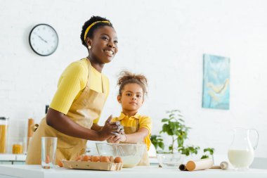 Afro-Amerikan çocuk ve neşeli anne mutfakta yemek pişirirken gülümsüyor. 