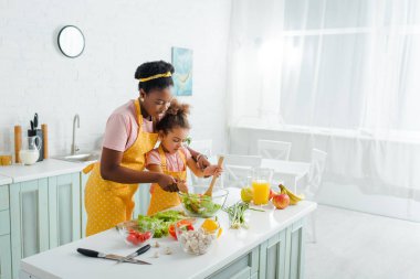 Afro-Amerikan anne ve çocuğu taze salatayı karıştırıyor. 