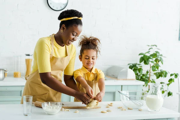 明るいアフリカ系アメリカ人の母親と幸せな子供がキッチンで餃子を彫る — ストック写真
