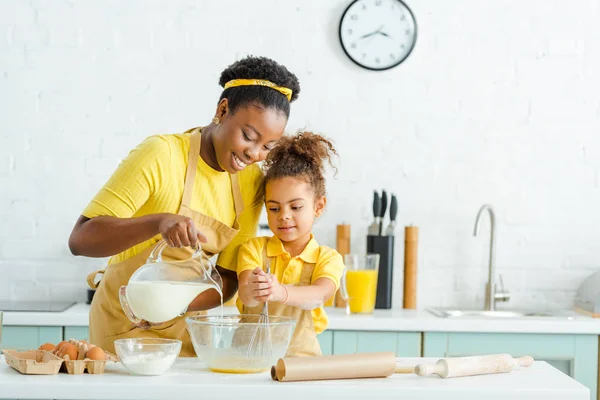 Cheerful African American Mother Pouring Milk Bowl Cute Daughter Kitchen — Stock Photo, Image