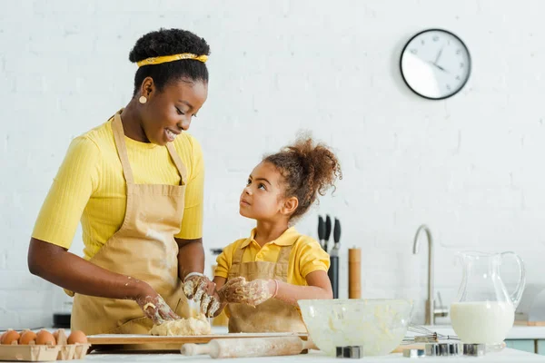 Cute African American Daughter Looking Cheerful Mother Kneading Dough Ingredients — ストック写真