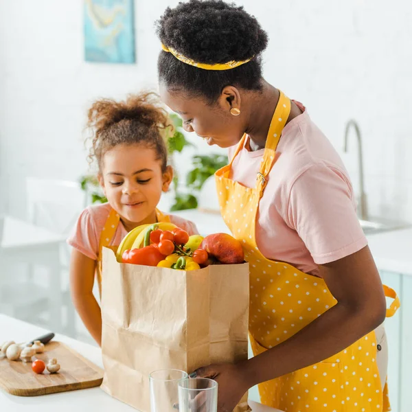 Glücklich Afrikanisch Amerikanische Mutter Und Tochter Betrachten Papiertüte Mit Lebensmitteln — Stockfoto